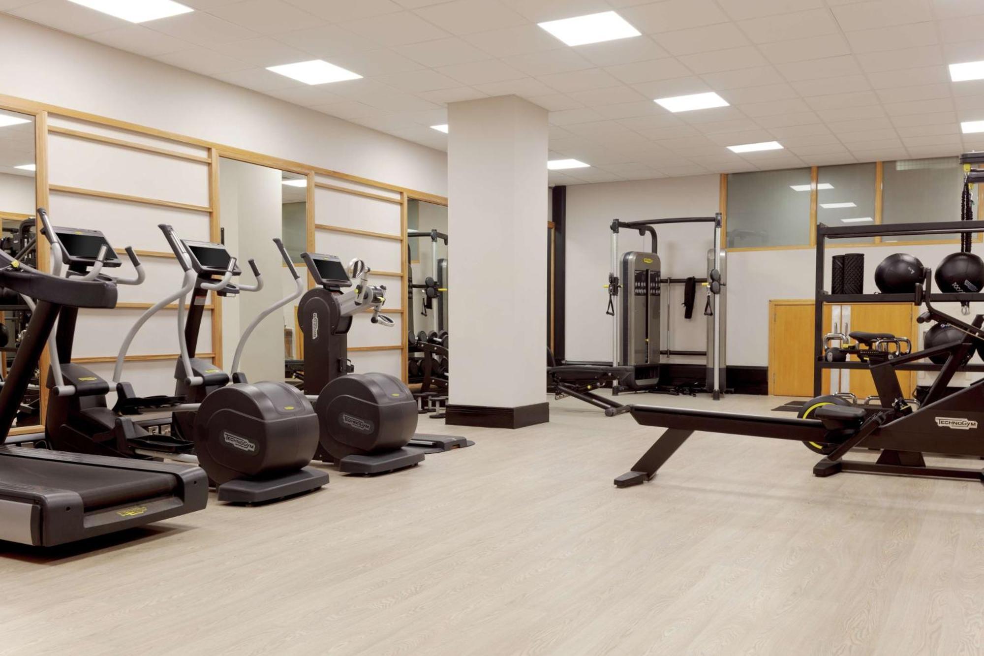 فندق هيلتون بيلفاست بلفاست المظهر الخارجي الصورة The photo shows a gym or fitness area. It features several exercise machines, including treadmills and elliptical machines. There's also a rowing machine and a multi-station strength training equipment. The space is well-lit with overhead lights and 